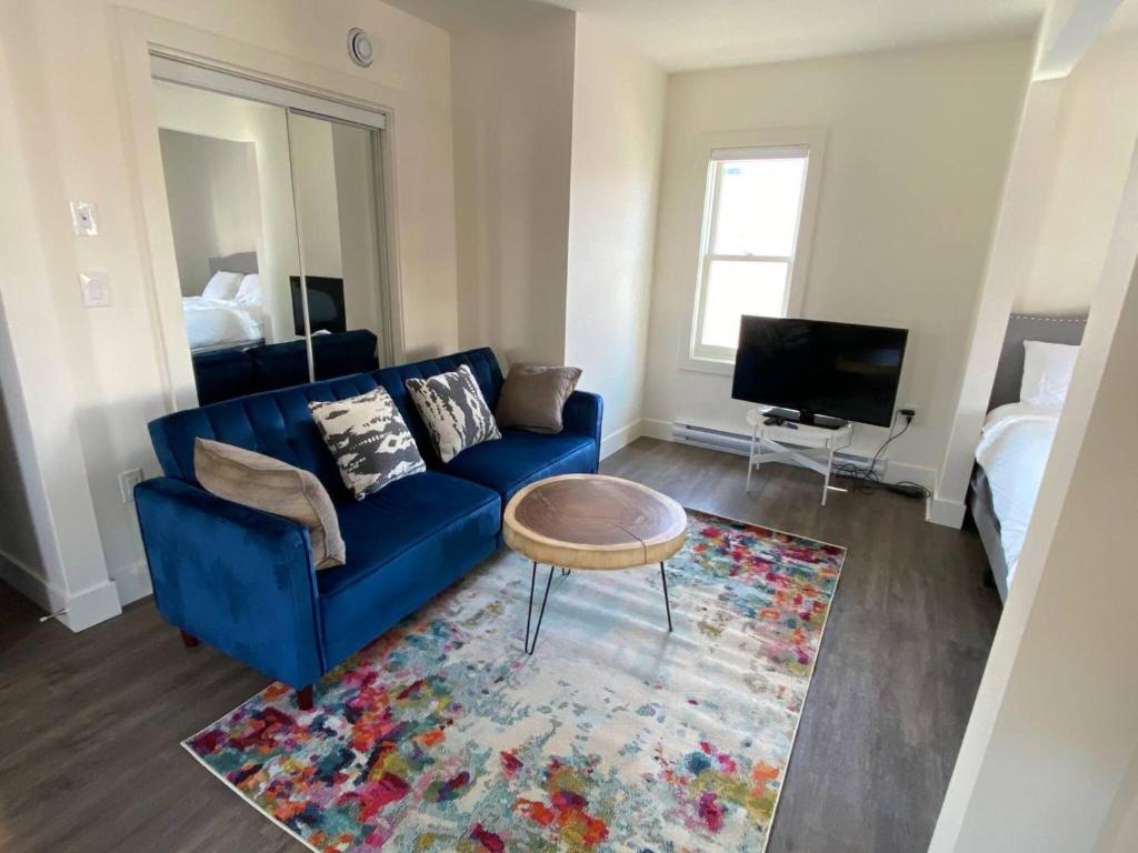 sala de estar con sofá azul y alfombra en Historical Building 1br 1ba Walk To Rogers Place en Edmonton