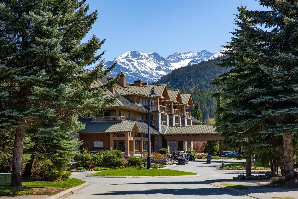 a large building with trees and mountains in the background at Lakeside Landing - Lake & Golf Course Views from Private Balcony - Whistler Platinum in Whistler