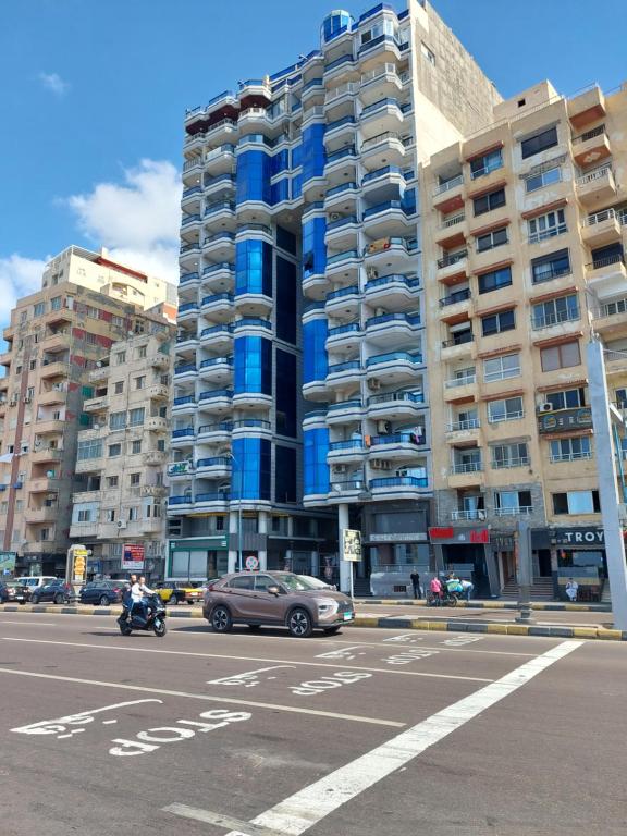 ein Auto, das vor einem hohen Gebäude eine Straße hinunterfährt in der Unterkunft Your Home Apartment in Alexandria