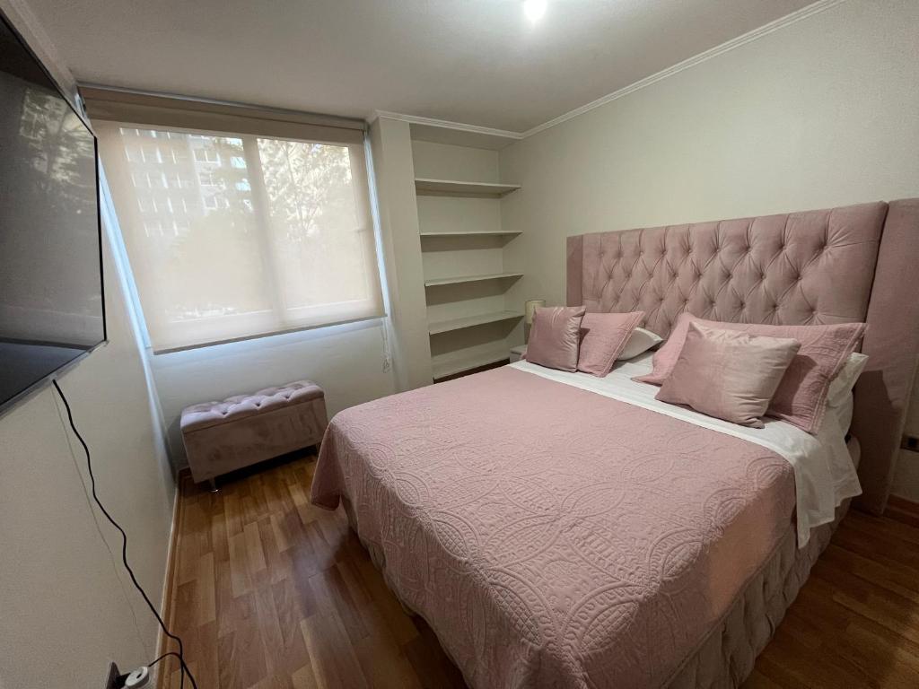 a bedroom with a bed with pink pillows and a window at Amoblados Chile Rent San Diego in Santiago