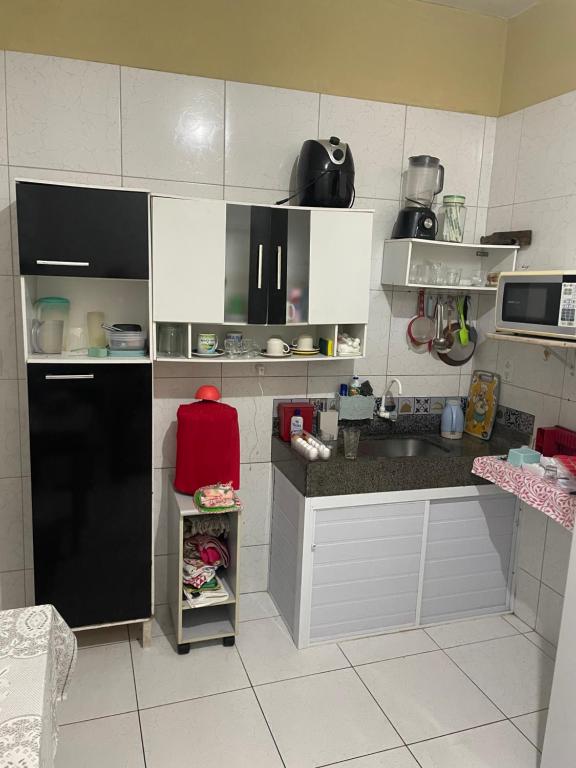 cocina con armarios blancos y nevera negra en ACONCHEGO Guest House en Aracati