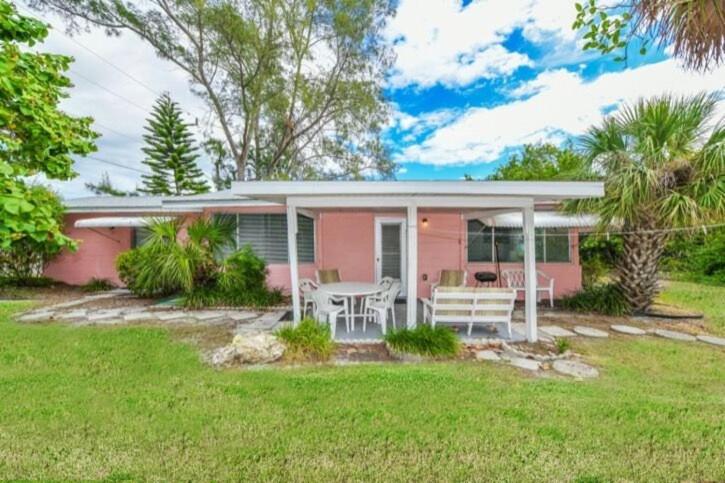 una casa rosa con una mesa y sillas en un patio en The Seashell, Private Home #54561 Home, en Holmes Beach