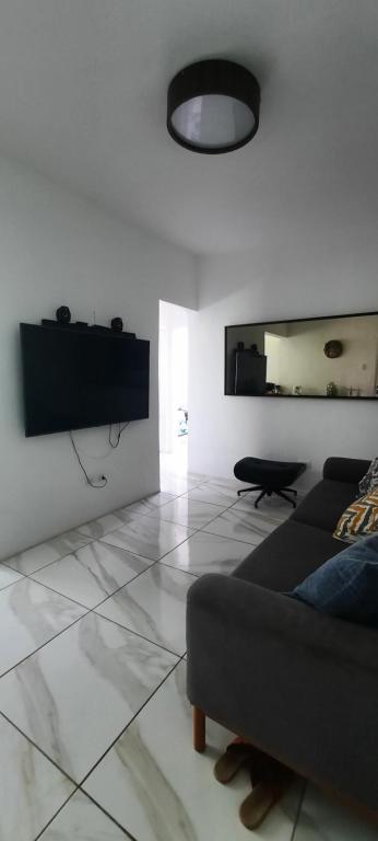 a living room with a couch and a tv on the wall at Apartamento mobiliado in Recife
