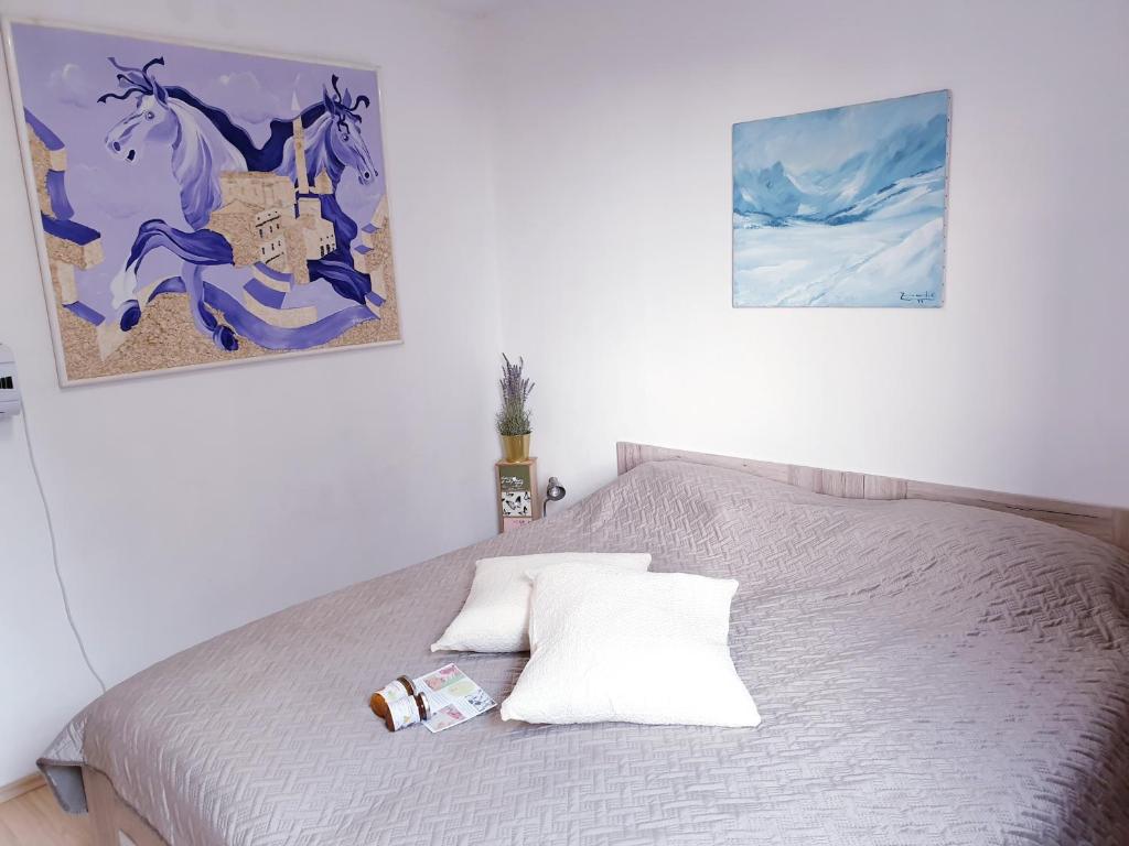 a bed in a bedroom with two pictures on the wall at LjubljanaArt Apartment in Ljubljana