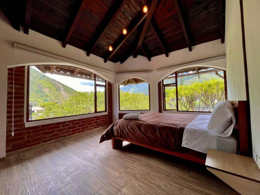 um quarto com duas janelas grandes e uma cama. em Room Privada Amanecer em Baños