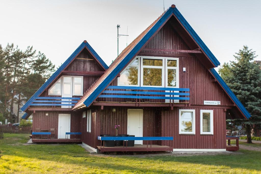 uma casa vermelha com um telhado azul em Pervalkos vetrunges em Neringa