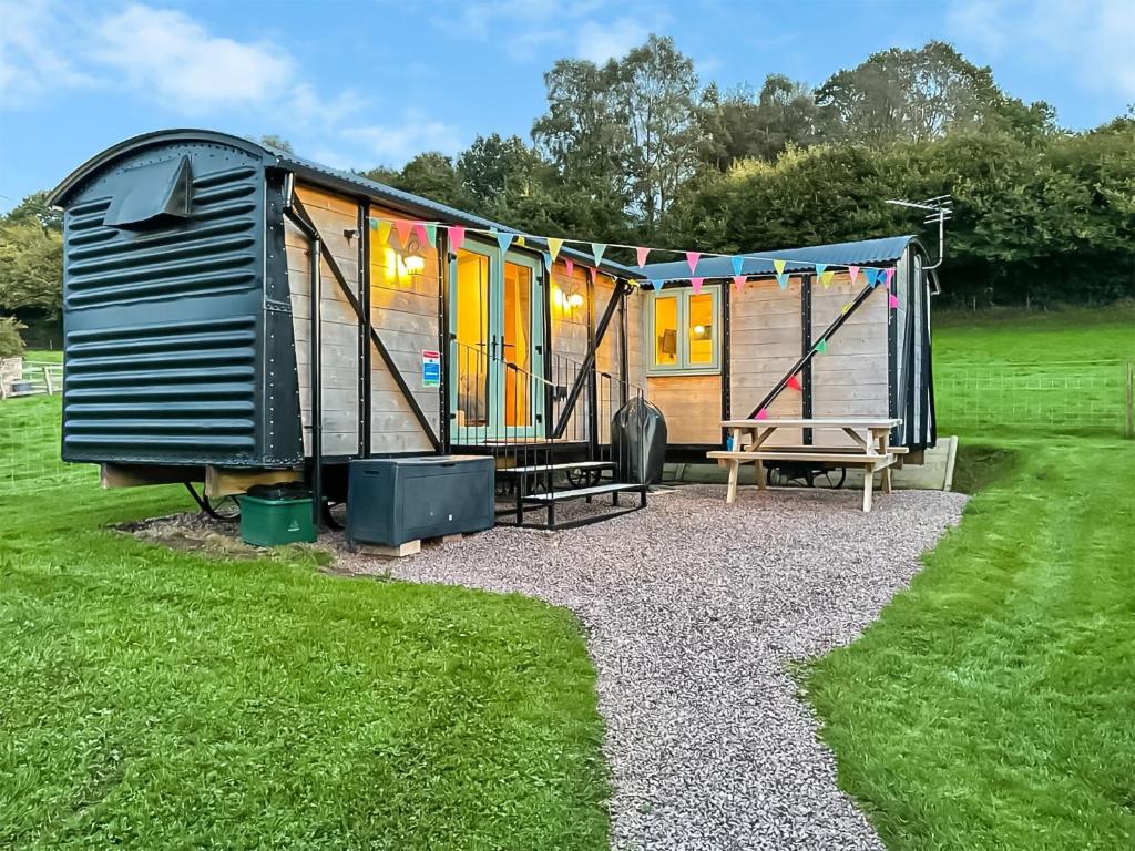 een tiny house met een speeltuin in een veld bij Hoarthorns Hideaway - Uk41687 in Coleford