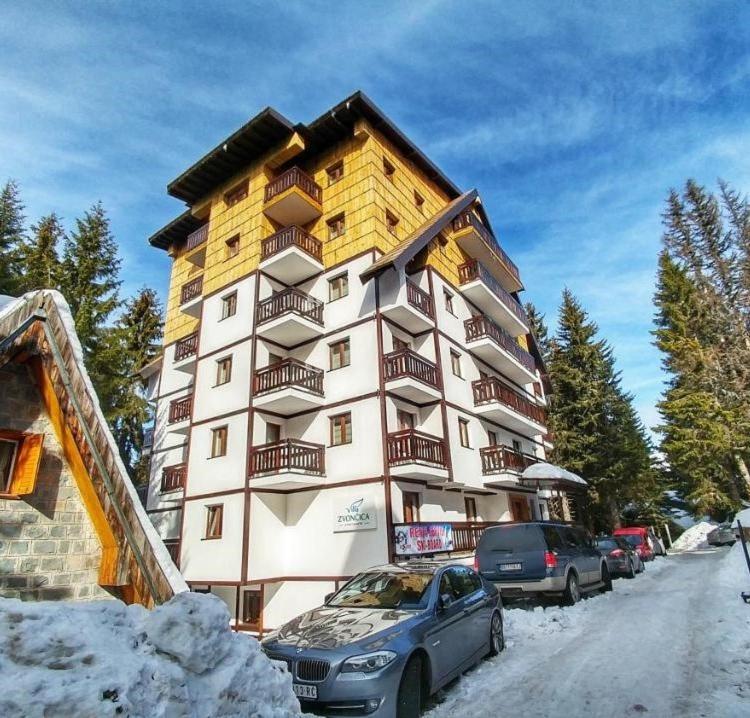 a large apartment building with cars parked in the snow at Vila Zvončica Apartman Z12 in Kopaonik