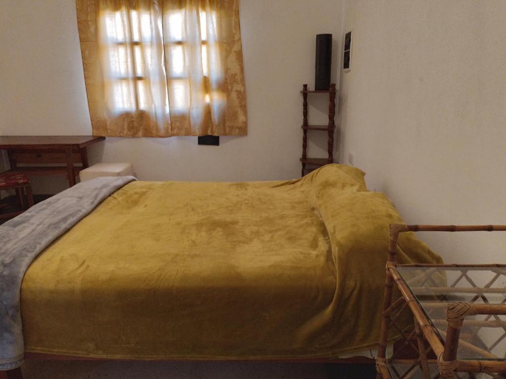 Una cama en una habitación con una manta amarilla. en La Casona en San Pedro de Jujuy