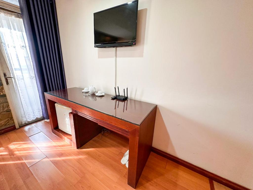 a desk in a room with a television on a wall at Khách Sạn Nam Anh in Can Tho