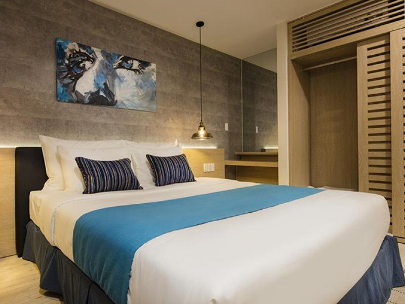 um quarto com uma grande cama branca com lençóis azuis em Lovely Room Oceanami Resort em Long Hai