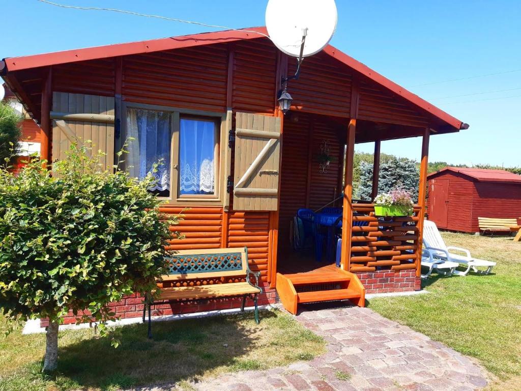 une cabine avec un toit rouge et un banc devant dans l'établissement Holiday cottages for 4 people, Rusinowo, à Rusinowo