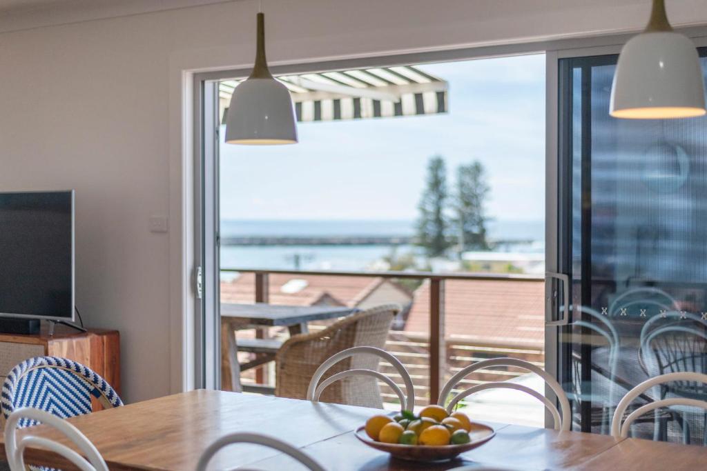 a dining room with a table with a bowl of fruit at Bimbajong Yamba - oceanstays in Yamba