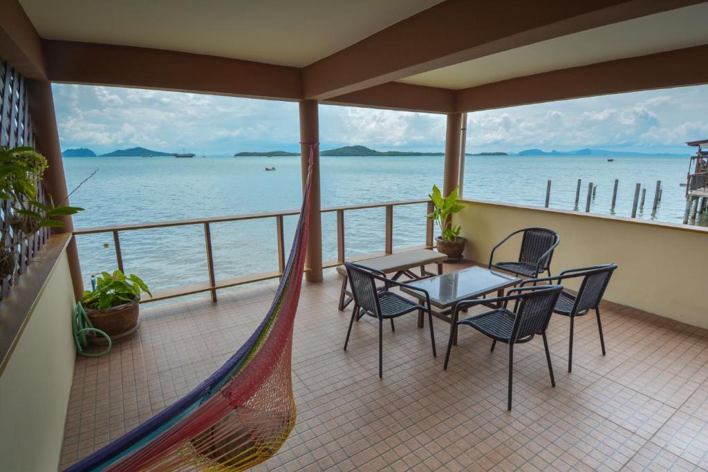 a balcony with a hammock and a table and chairs at Lanta New House in Ko Lanta