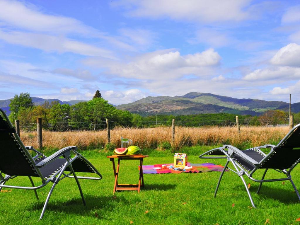 two lawn chairs and a table in a field at Gors Y Gader in Llanelltyd