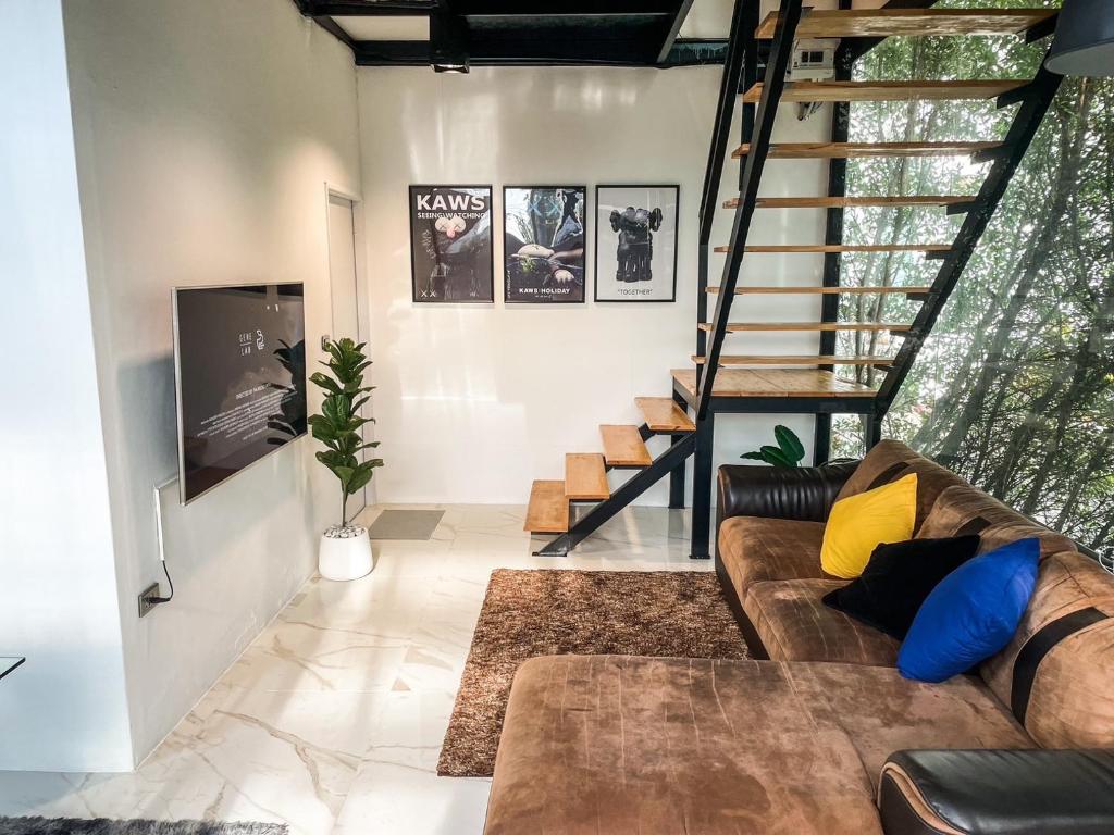 a living room with a couch and a staircase at Peaceful & Contemporary Duplex Escape in Ban Thap Nang