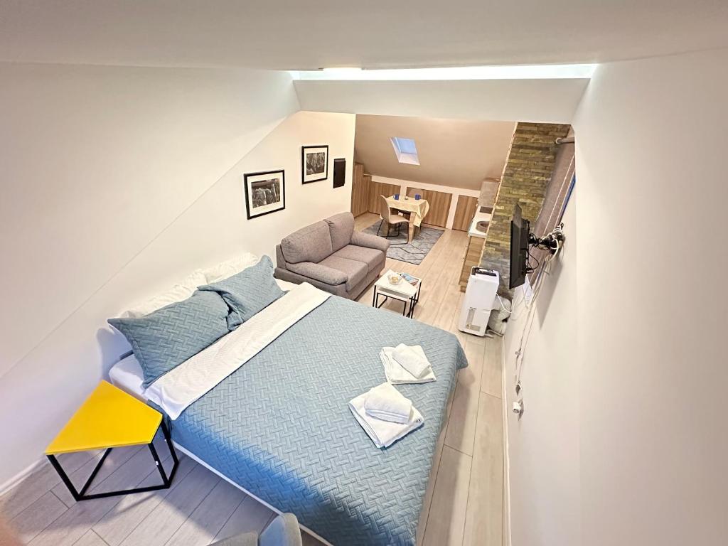 - une chambre avec un lit bleu et un canapé dans l'établissement Lovely studio apartament, à Pristina