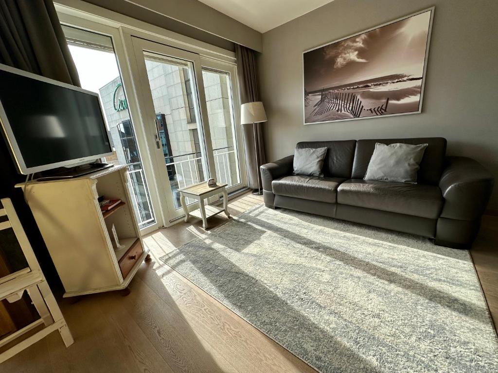a living room with a couch and a television at Charming Apartment direct access beach Blankenberge in Blankenberge