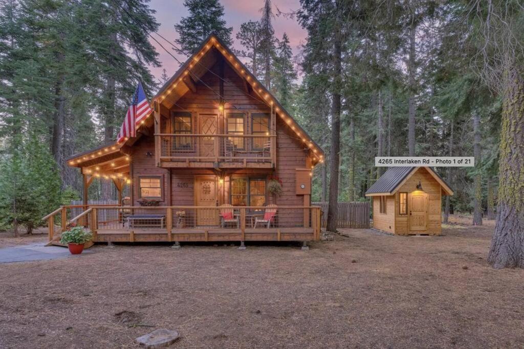 a log cabin in the woods with an american flag at Cozy Pet-Friendly Cabin w Private Hot Tub Fenced In Yard Walk to HOA Beach & Pier in Homewood