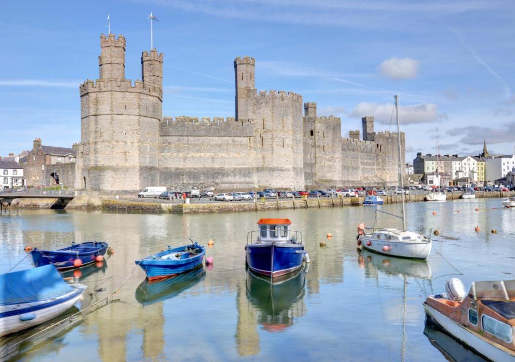 a group of boats in the water in front of a castle at Ty Nain in Caernarfon