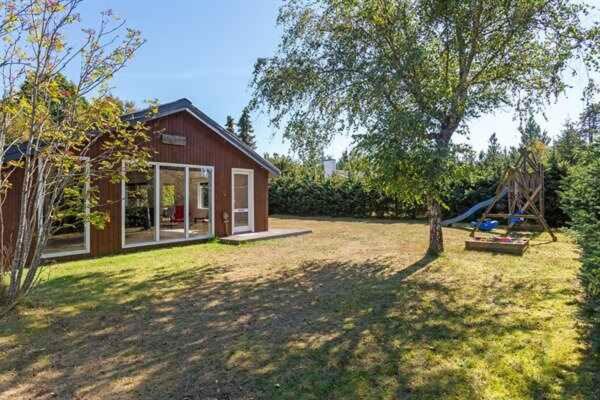 ein rotes Haus mit einem Hof mit Schaukel in der Unterkunft Holiday Home In Quiet Neighborhood in Hals