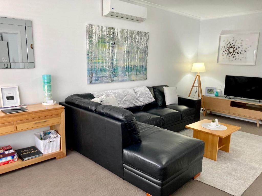 a living room with a black leather couch and a television at Rosa's Apartment in Mount Gambier