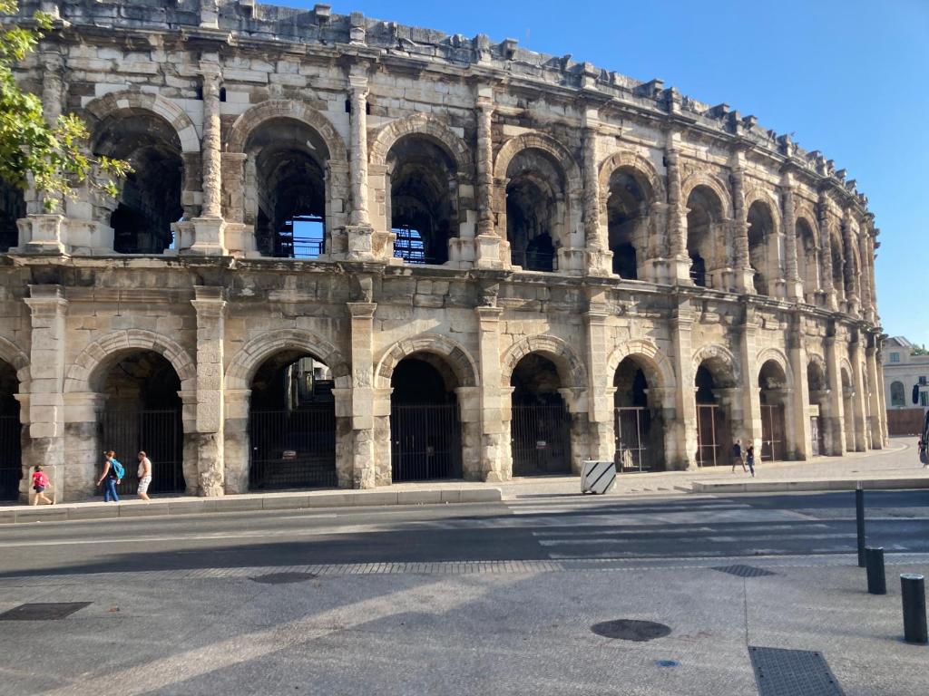 een groot gebouw waar mensen voor lopen bij Coup de coeur avec terrasse à 3 minutes des Arènes in Nîmes