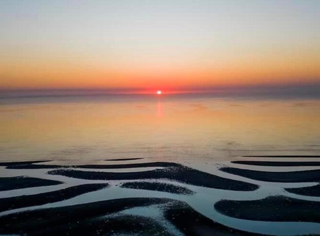 a sunset over the ocean with ripples in the water at Beachmere Palms Motel in Beachmere