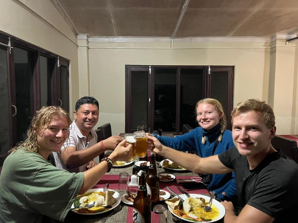 a group of people sitting at a table drinking beer at Sauraha BnB in Sauraha