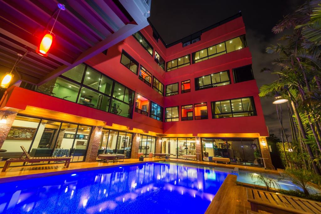 a hotel with a swimming pool in front of a building at Thongtara House Boutique Srinakarin in Bangkok