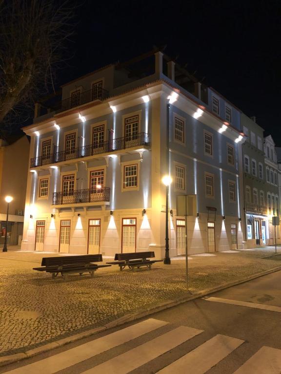 Un grand bâtiment blanc avec des lumières allumées la nuit dans l'établissement Dona Maria Hotel, à Figueira da Foz