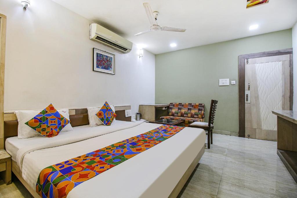 a bedroom with a large bed and a chair at FabHotel Smriti Star in Bhopal