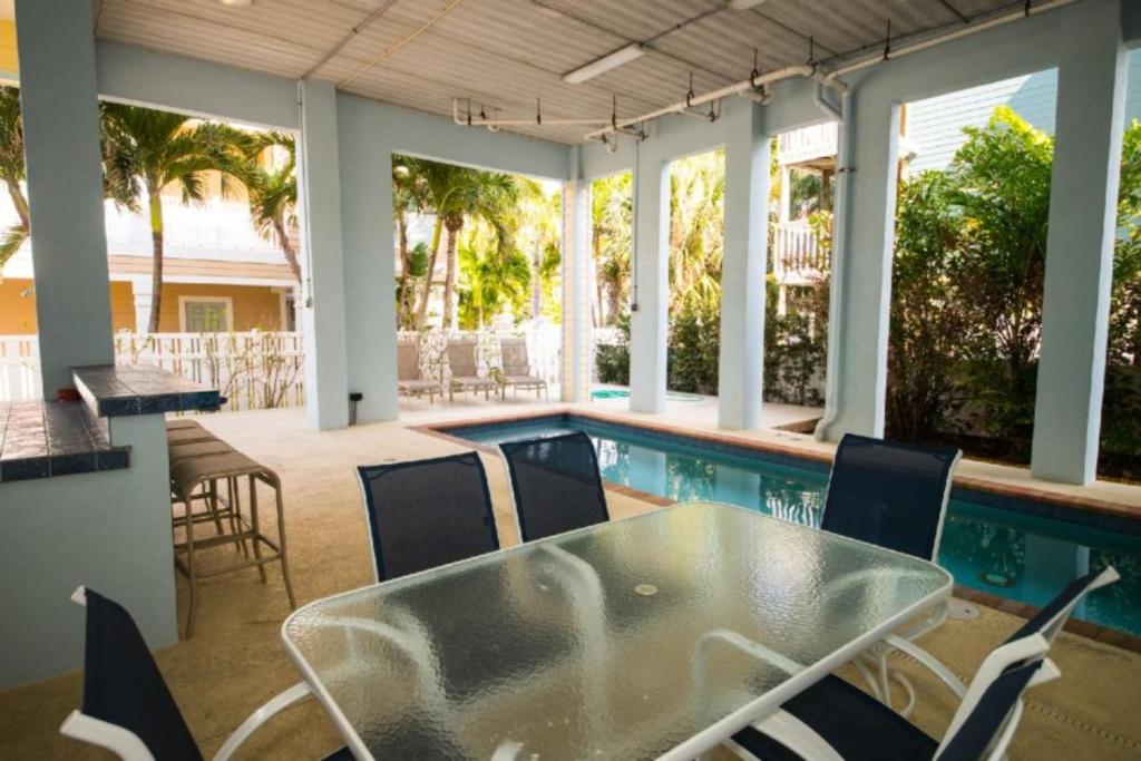 un patio con mesa y sillas junto a una piscina en 102 6Th St S- Upstairs Home, en Bradenton Beach