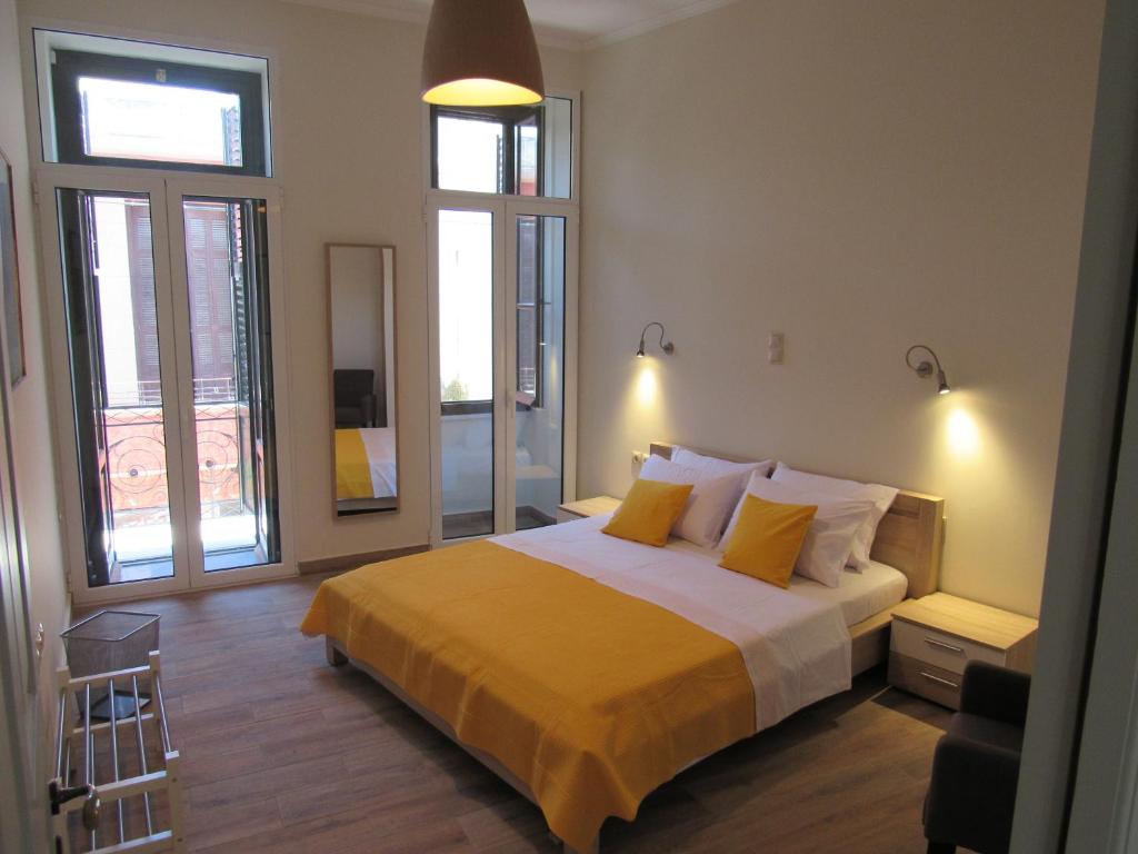 a bedroom with a bed with yellow sheets and windows at Kerameion in Athens