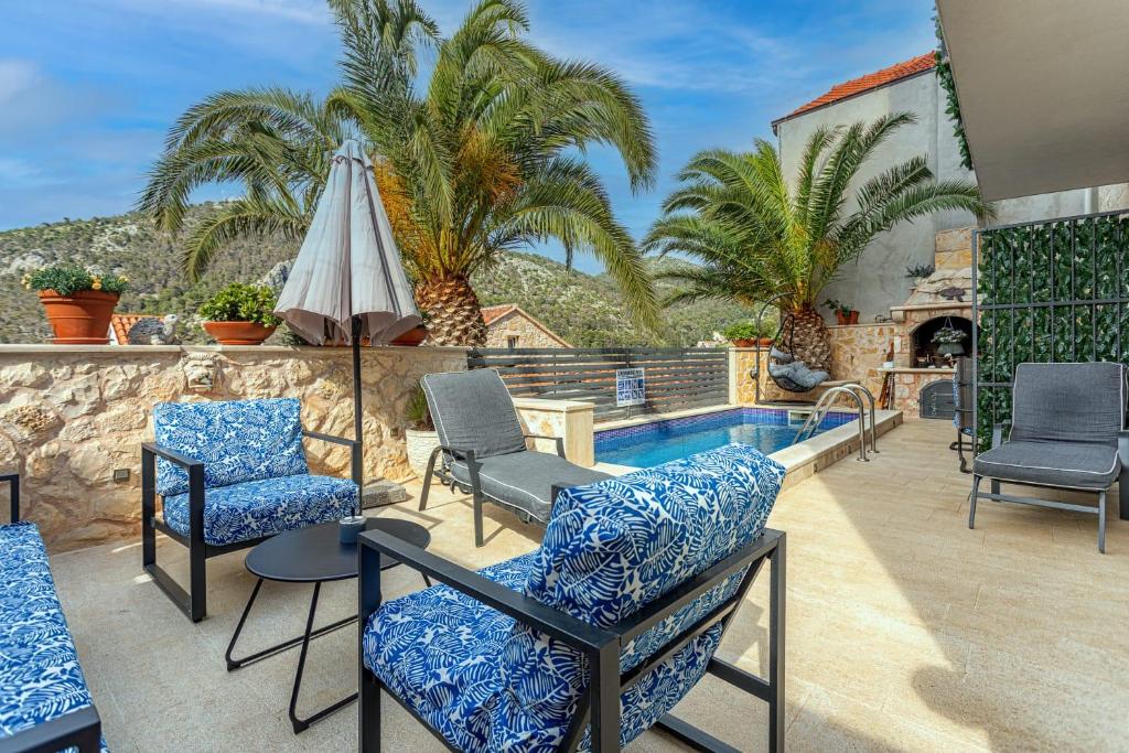 une terrasse avec des chaises et un parasol ainsi qu'une piscine dans l'établissement Villa Capitis in the center- Luxury apartment with swimming pool, à Hvar