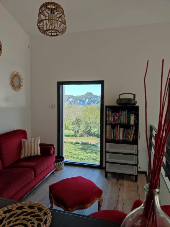 a living room with a red couch and a window at Les Terrasses du Phenix in Saint Alban Auriolles