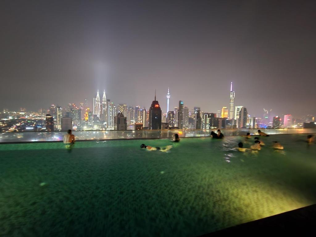 a group of people swimming in a pool with a city skyline at Regalia Suites Kuala Lumpur KLCC in Kuala Lumpur