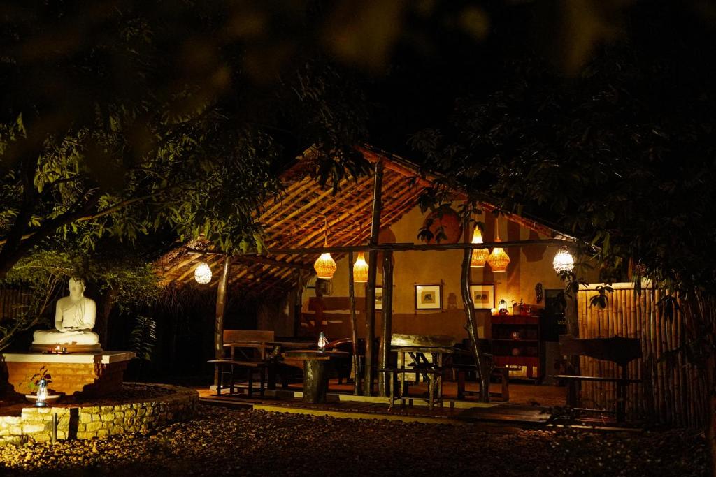 a small house with a statue in the yard at night at River Glamping by Gaga bees in Udawalawe
