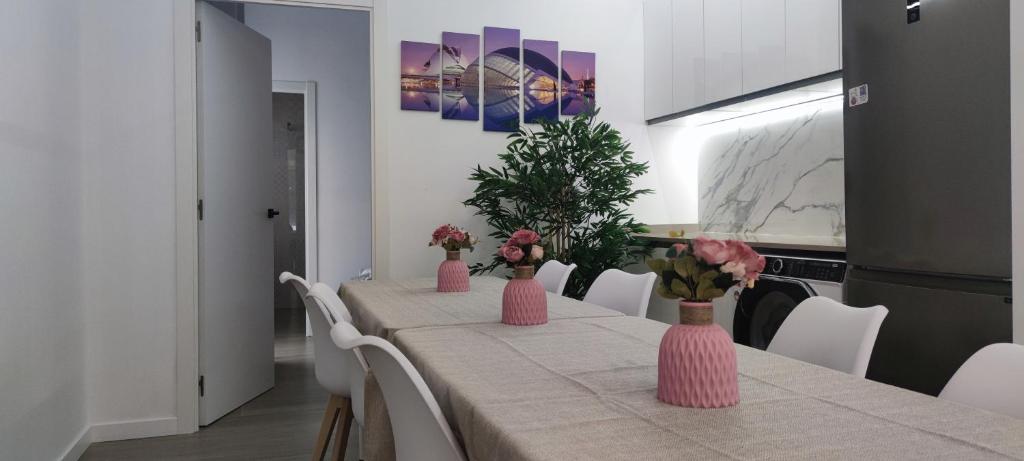 una mesa de comedor con jarrones rosas con flores en Apartamento 4 habitaciones 2 baños Ciudad de las Ciencias VT-55209-V, en Valencia