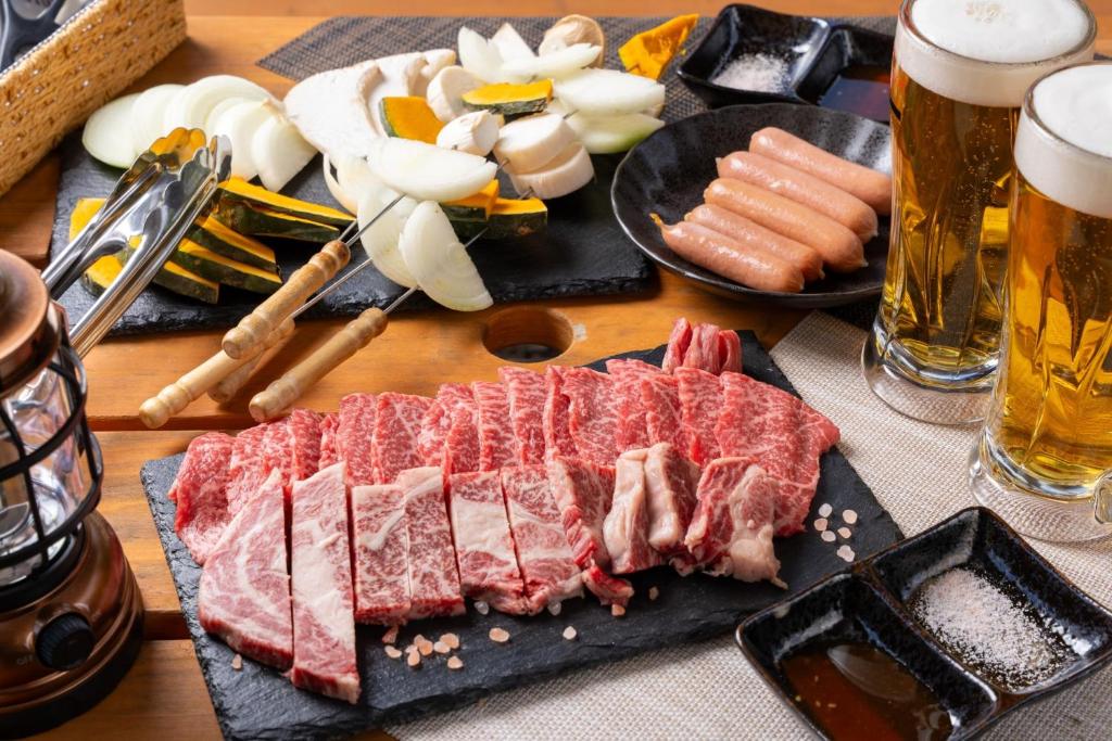 una mesa con carne y otros alimentos y cerveza en Glamchette Okayama -Glamping & Auto Camp- - Vacation STAY 44598v, en Mimasaka