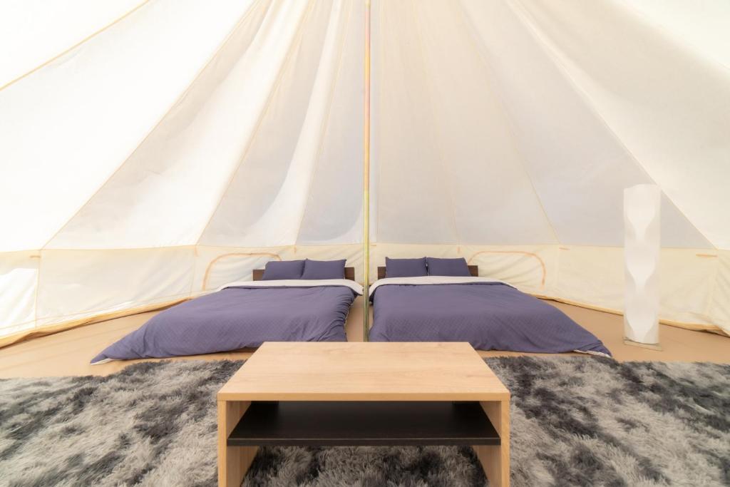 a tent with two beds and a table at Glanchette岡山∼グランピング＆オートキャンプ∼ 