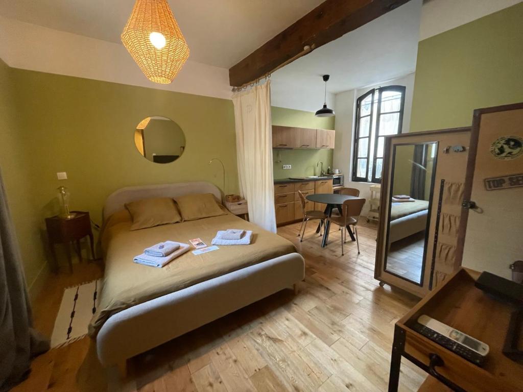 a bedroom with a bed and a table and a mirror at Studio de Charme à la Roquette in Arles