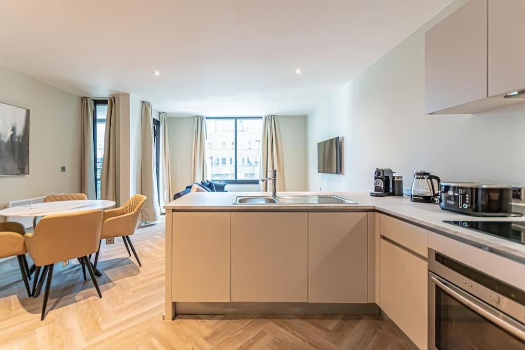 a kitchen with a sink and a table with chairs at Luxurious 1 Bed - CITY VIEW in Liverpool