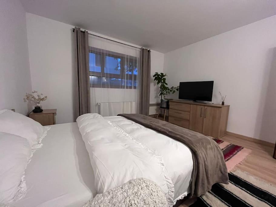 Un dormitorio con una gran cama blanca y una ventana en Rustic house en TÄƒuÅ£ii MÄƒgheruÅŸ