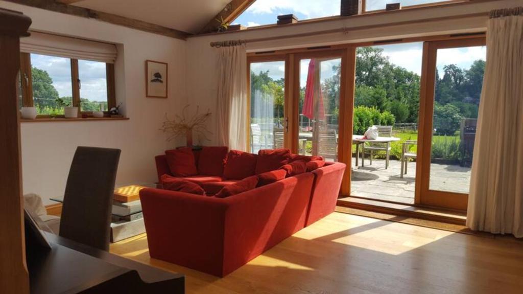 a living room with a red couch and sliding glass doors at Prestwick Oak - Sleeps 10-14 - Group Accommodation for Family or Friends in Haslemere