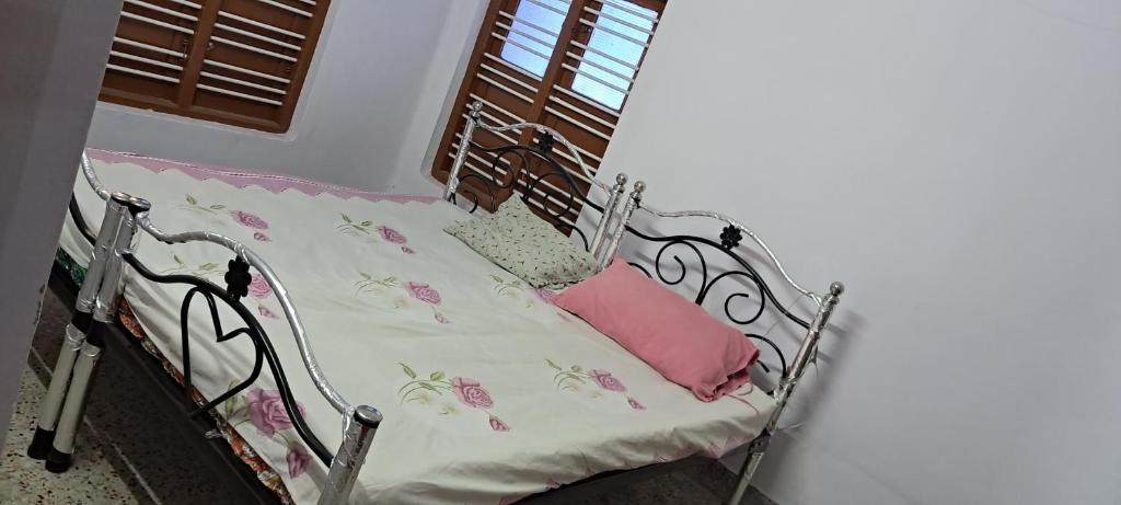 Una cama de metal con una almohada rosa. en Major Madi Residency, en Pondicherry