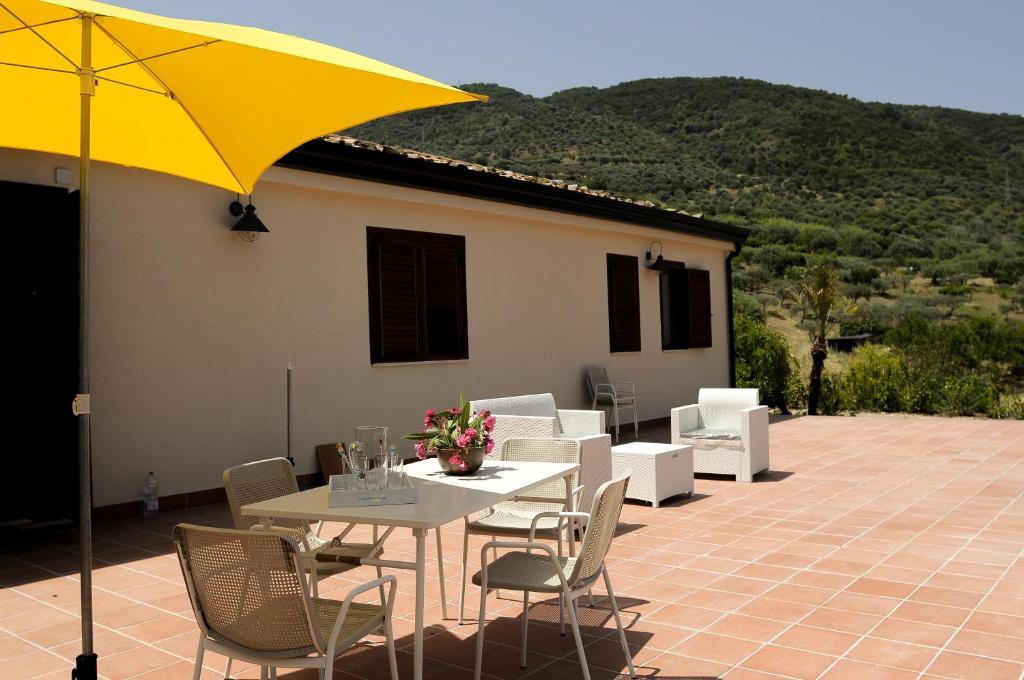 a patio with a table and chairs and a yellow umbrella at Villa Bruca 2 appartamenti al mare in Caronia Marina