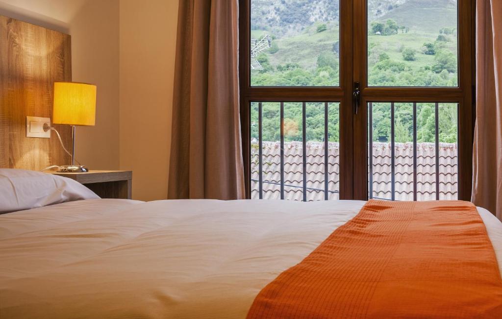 een slaapkamer met een bed en een groot raam bij Apartamentos El Caxigu in Arenas de Cabrales