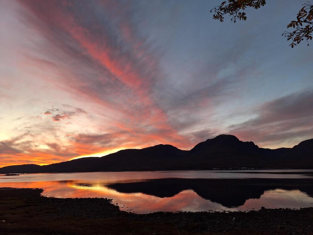 a sunset over a lake with mountains in the background at Kishorn Seaside House - Bed and breakfast in Strathcarron