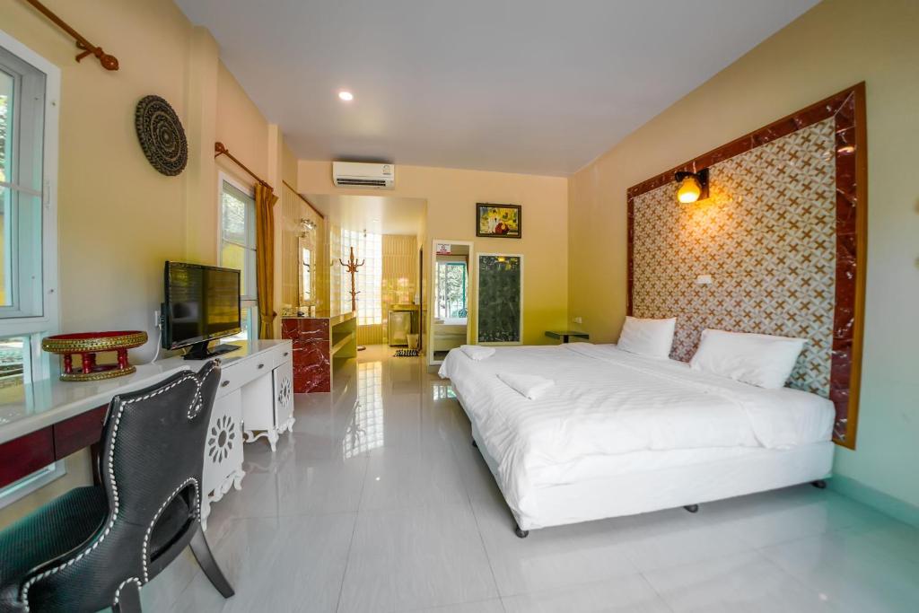 um quarto com uma cama branca e uma televisão em Happy Garden Resort Betong em Betong